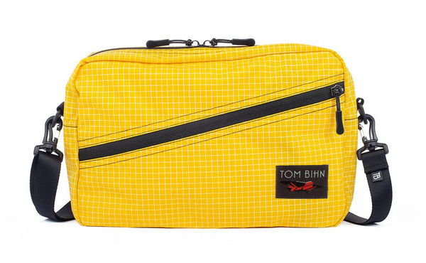 A Packing Cube Shoulder Bag in Solaris (yellow with white grid) 200 Halcyon with a 1-inch shoulder strap attached.